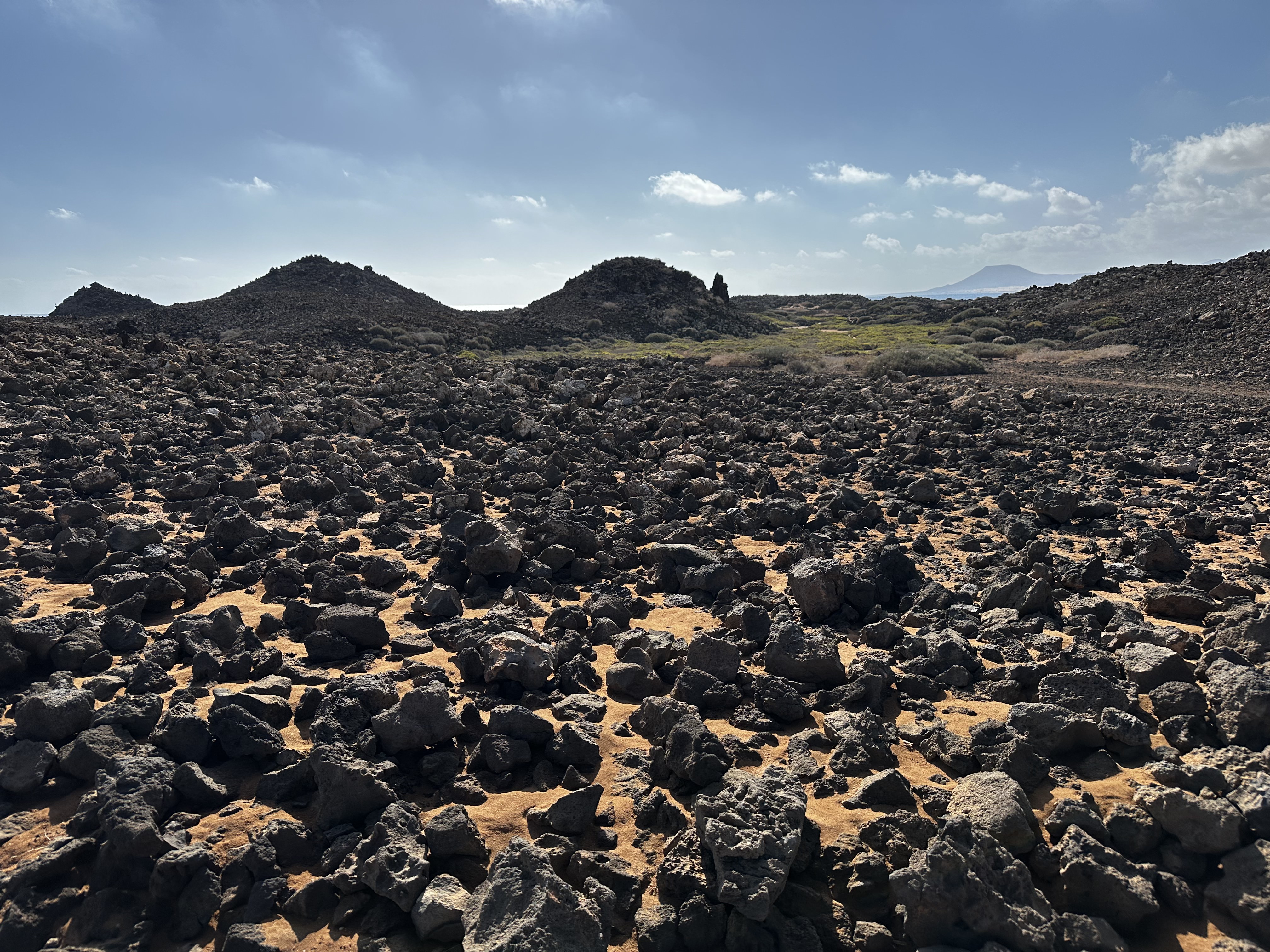 The dramatic volcanic malpaís of Isla de Lobos — black lava rocks stretching to the horizon under a wide sky