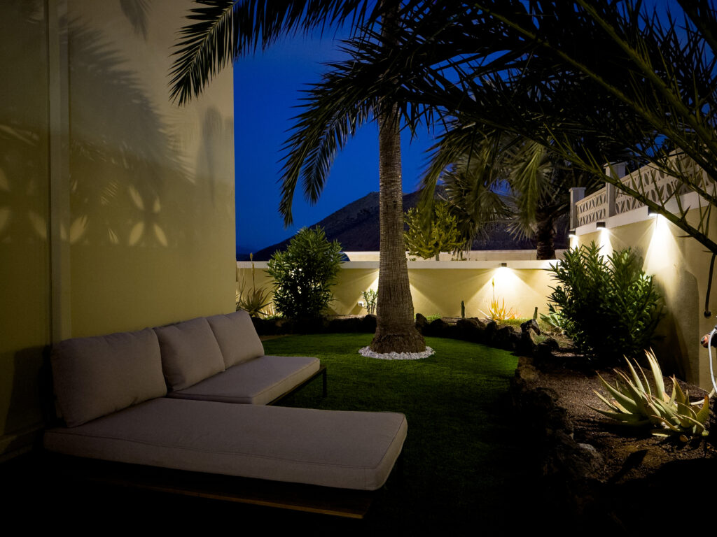 Villa Solymar side garden by night — illuminated palm tree and daybed