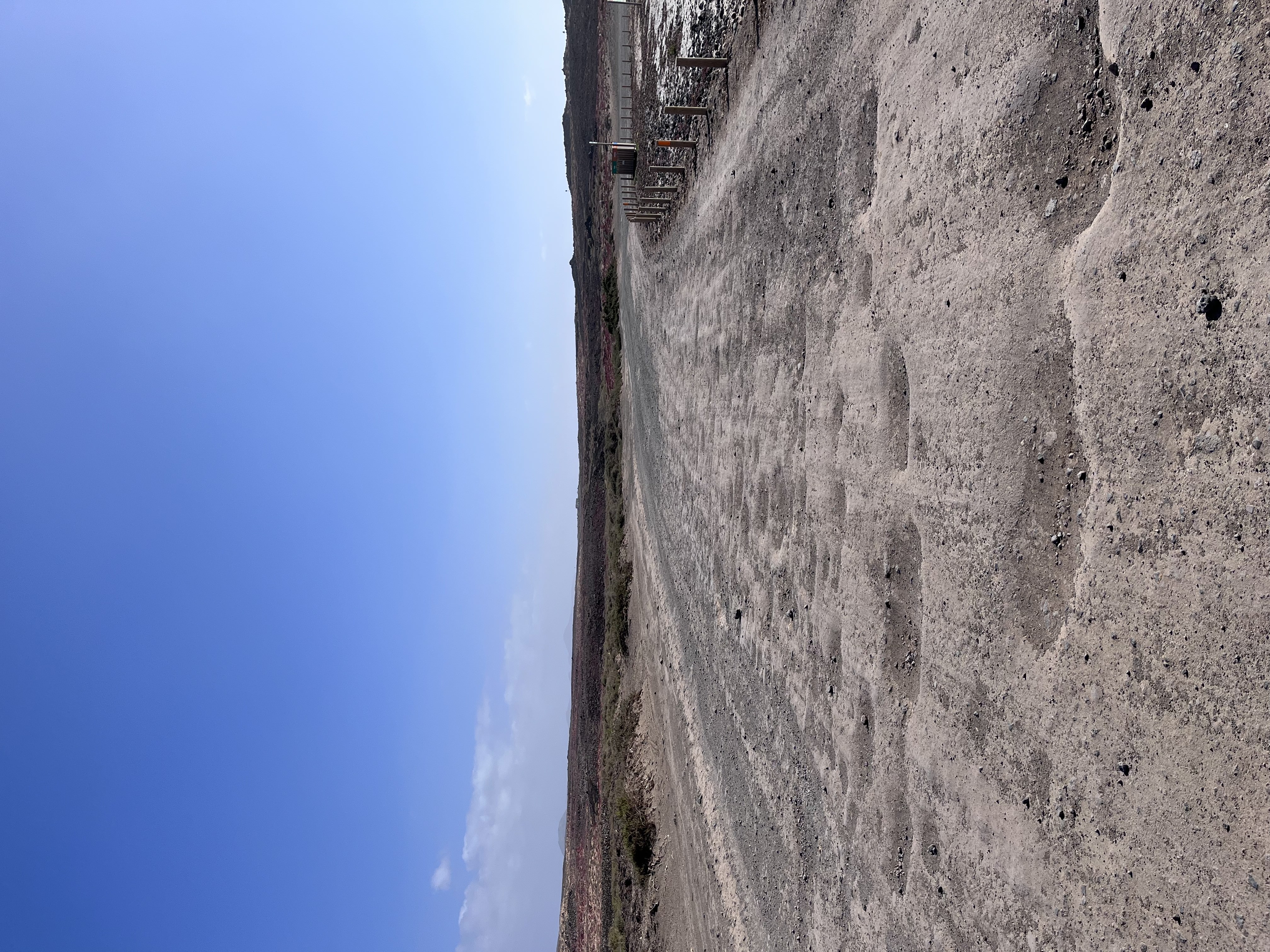 The volcanic dirt track leading into Majanicho — wide, bare, and strikingly empty under a deep blue sky